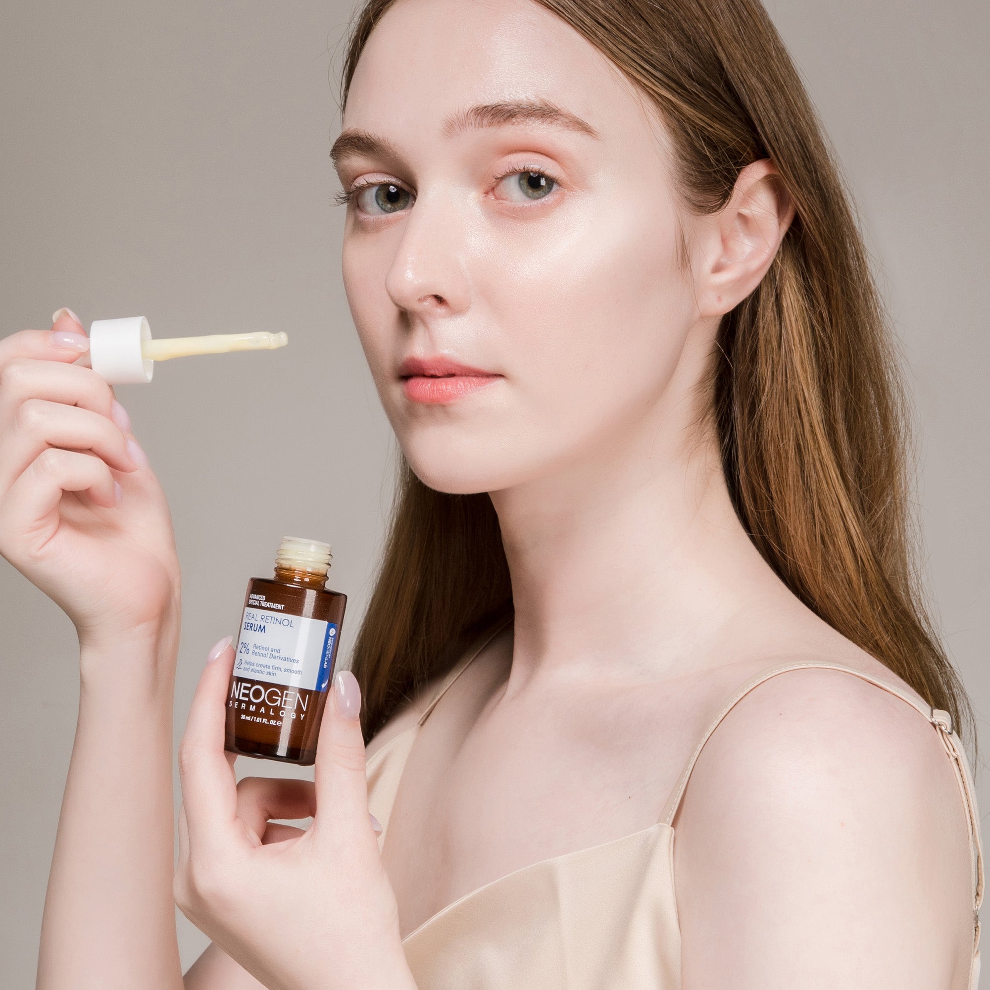 NEOGEN Real Retinol Serum 30ml : femme appliquant le sérum de la marque NEOGEN, flacon et embout goutteur sur fond clair.