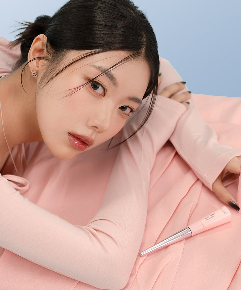 NEOGEN  Slim Metal Mascara 6ml de la marque NEOGEN, présentée en flacon rose, maquillage sur fond pastel, maquilleuse