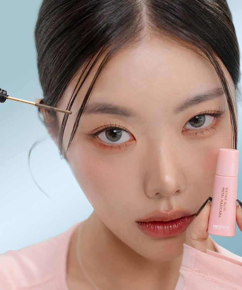 NEOGEN  Slim Metal Mascara 6ml, marque NEOGEN : application du mascara sur cils, maquillage, fond bleu clair.
