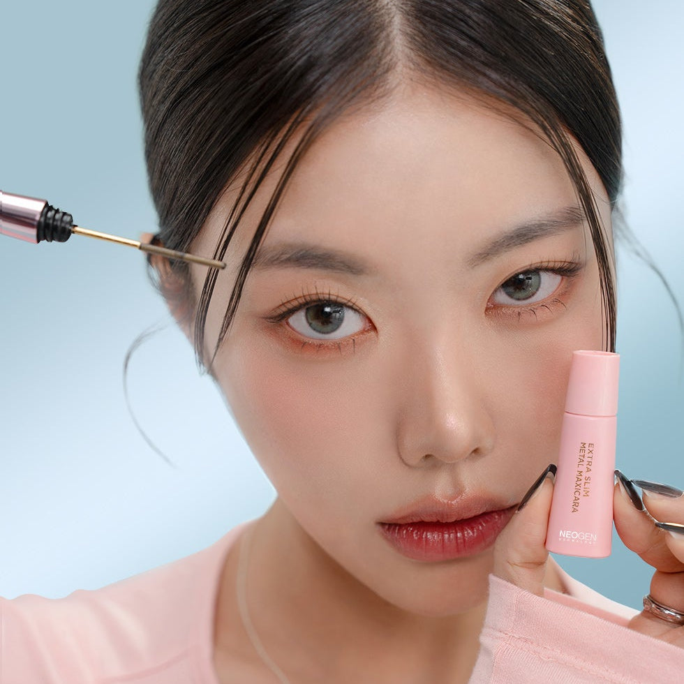 NEOGEN  Slim Metal Mascara 6ml, marque NEOGEN : application du mascara sur cils, maquillage, fond bleu clair.