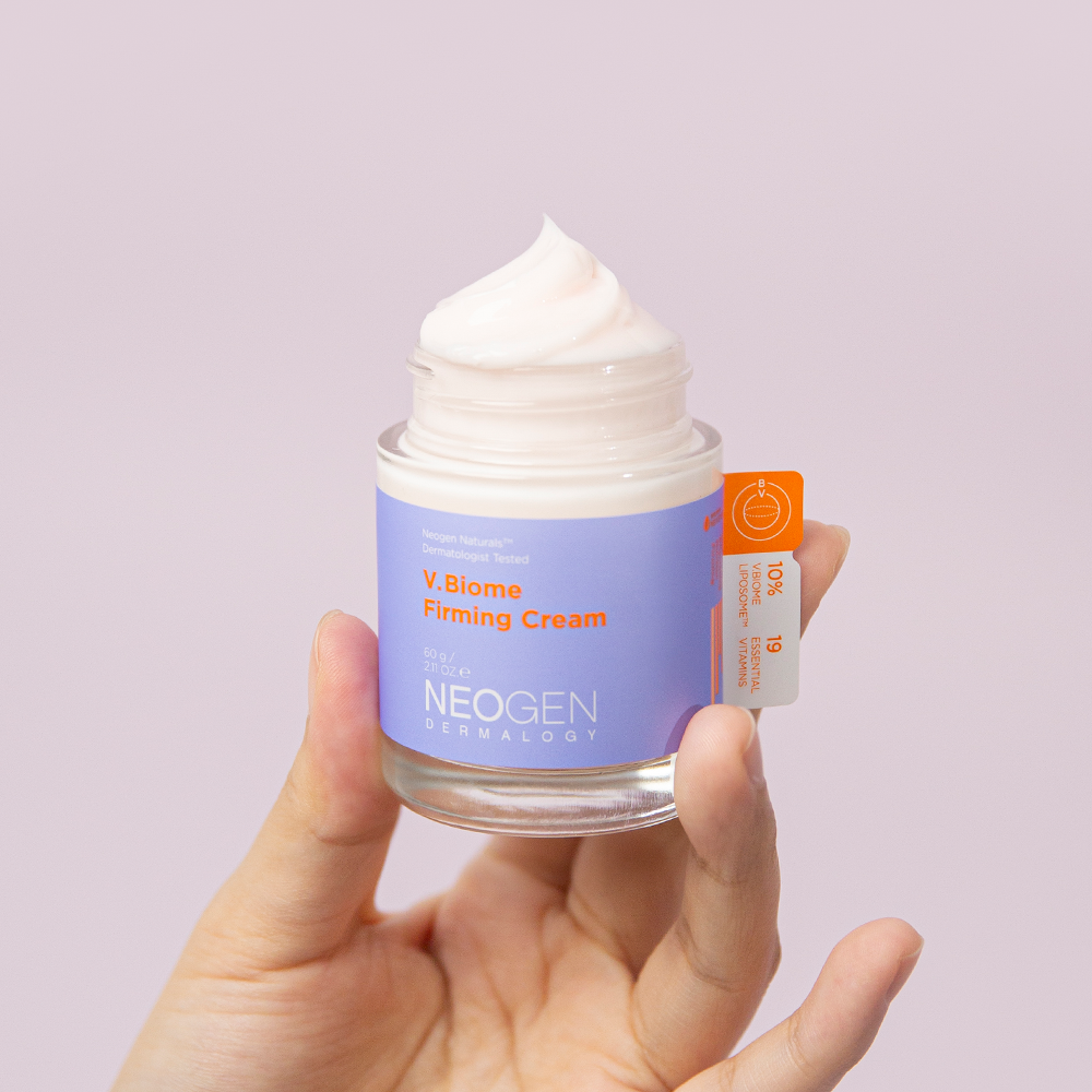 NEOGEN V Biome Firming Cream 60g, crème raffermissante de NEOGEN Dermalogy en pot, mains tenant le produit sur fond clair.