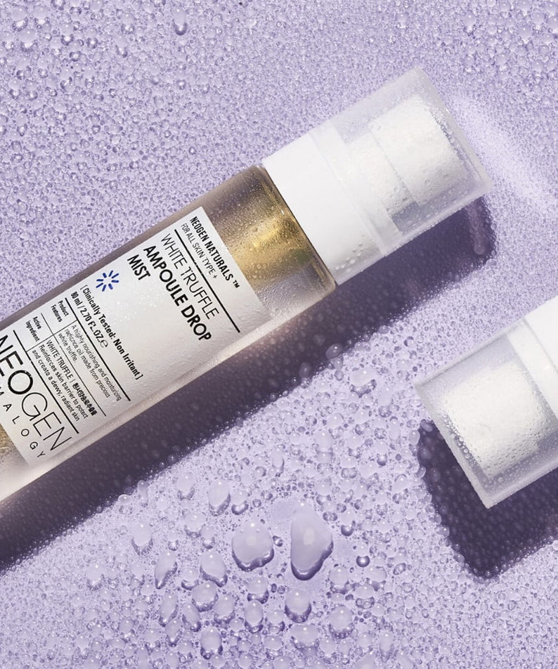 NEOGEN White Truffle Ampoule Drop Mist 80ml de NEOGEN, flacon sur fond violet avec gouttes d’eau, ambiance beauté spa