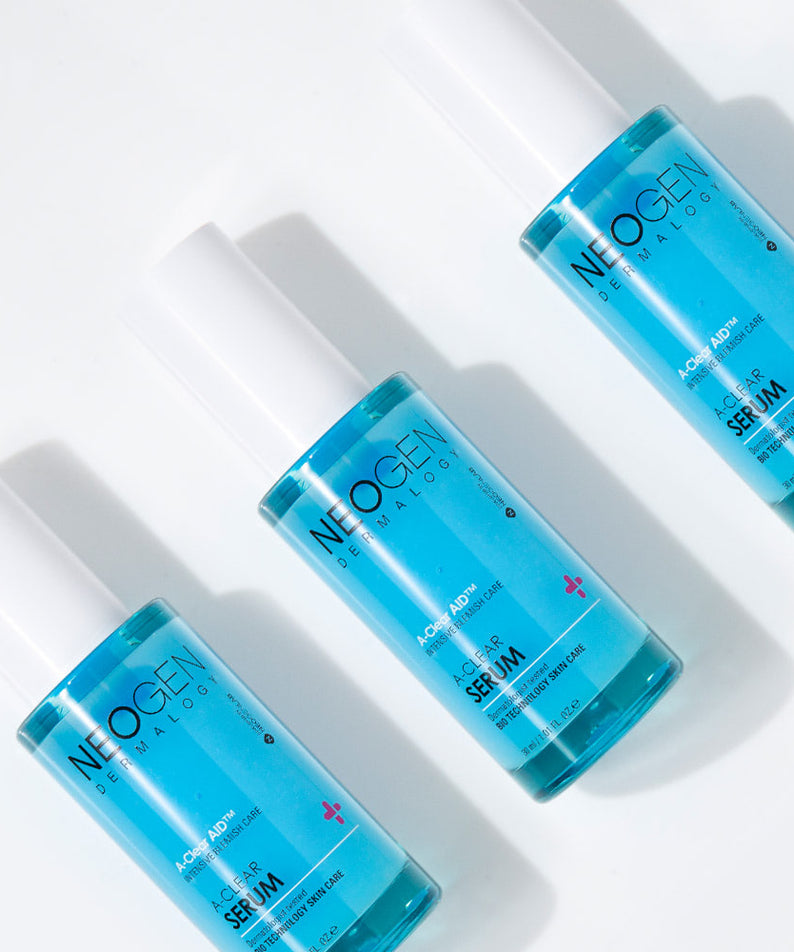 Trois flacons de NEOGEN A Clear Serum 30ml disposés sur une surface blanche, montrant leur design épuré et moderne.
