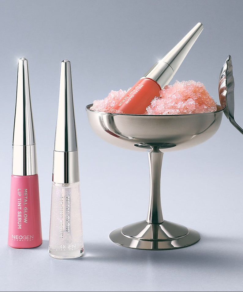 NEOGEN Metal Glow Lip Tint Serum NEOGEN, flacons de gloss lumineux sur fond clair, avec effet pailleté.