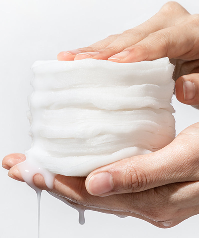 Gros plan sur les NEOGEN Niacinamide Glow Up Daily Mask Pads 40 Sheets tenus dans une main, crème apparaissant luxueuse et hydratante.