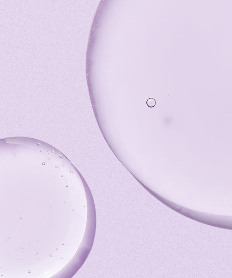 Texture du NEOGEN Real Bakuchiol Firming Serum 30ml sur fond violet, gouttes de sérum pour soin anti-âge.