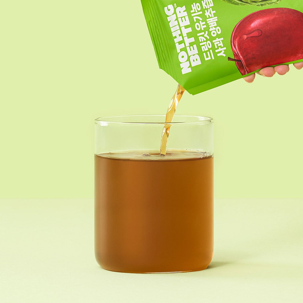 Plan rapproché: NOTHING BETTER Drinkit Organic Applr Cabbage Juice 100ml 24 Packets, bouteille verte verse du jus dans verre, fond vert.