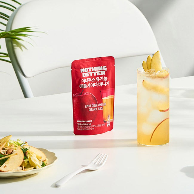 NOTHING BETTER Inner Juice Apple Cider Vinegar Cleanse Juice (X24) sur table, ambiance bien-être, bouteille et verre de jus au citron
