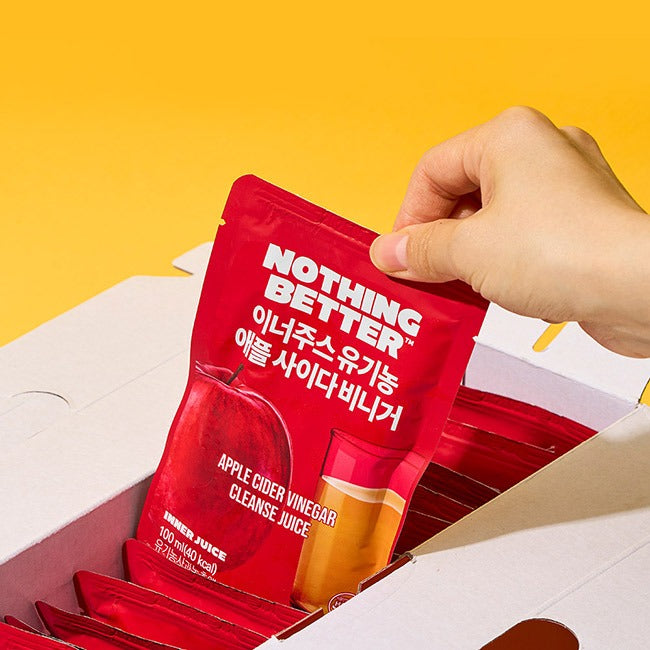 Main tenant NOTHING BETTER Inner Juice Apple Cider Vinegar Cleanse Juice (X24) sur fond jaune, pack en carton ouvert.