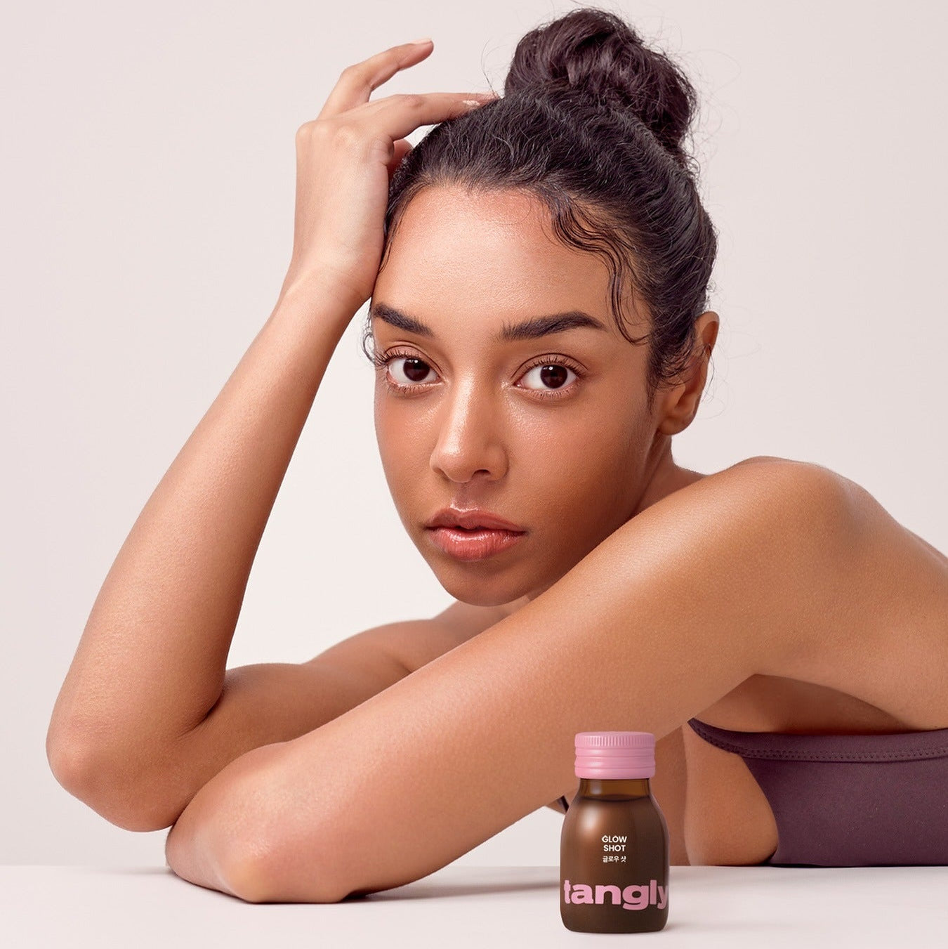 NOTHING BETTER Tangly Glow Shot 7 Bottles, produit Tangly sur table : femme tenant ses cheveux, fond clair, cosmétique glow