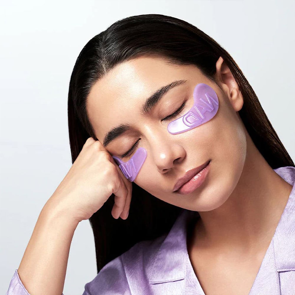 NUMBUZIN No. 9 NAD Collagen Overnight Selfie Patch, marque NUMBUZIN : femme applique des patchs violets sur le visage.