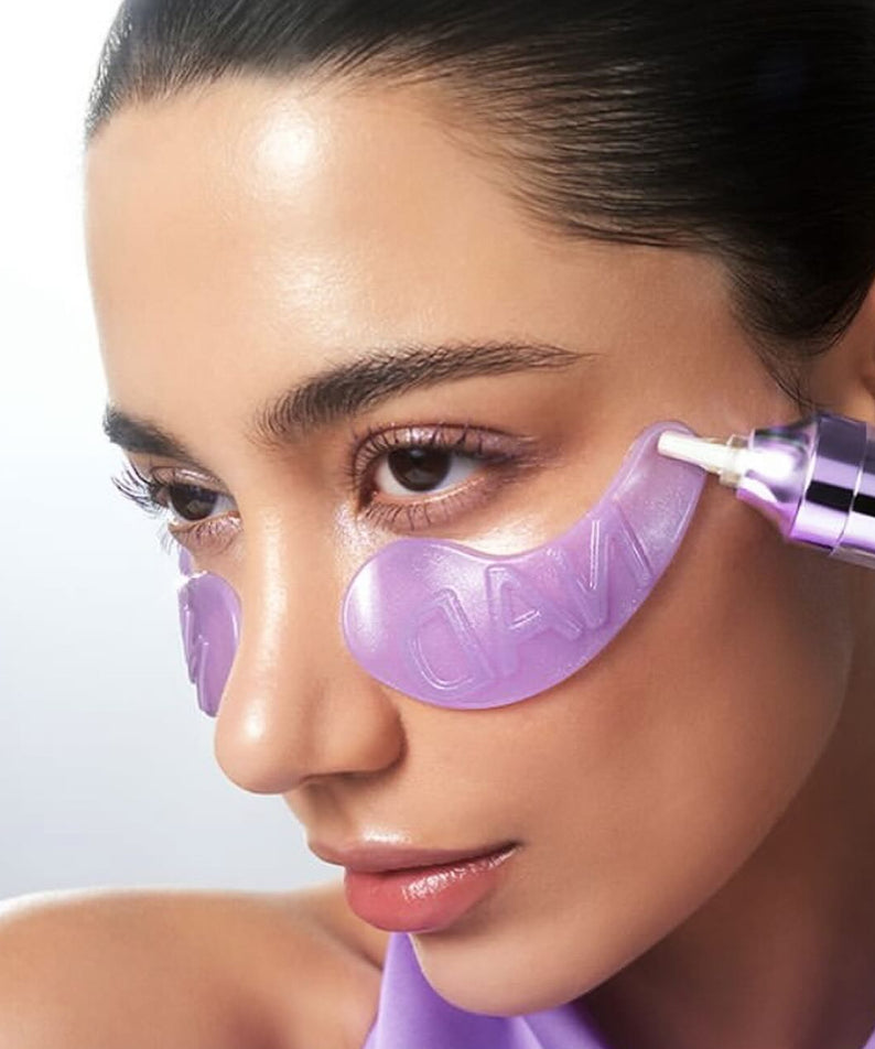NUMBUZIN No. 9 NAD Collagen Overnight Selfie Patch : femme applique des patches violets sur le visage, sérum en action.
