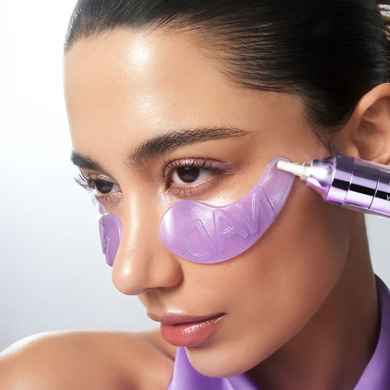 NUMBUZIN No. 9 NAD Collagen Overnight Selfie Patch : femme applique des patches violets sur le visage, sérum en action.