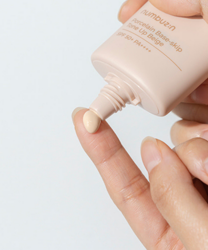 Crème NUMBUZIN No.3 Porcelain Base-Skip Tone Up Beige SPF50+ PA++++ appliquée sur le doigt, hydratation et protection solaire.