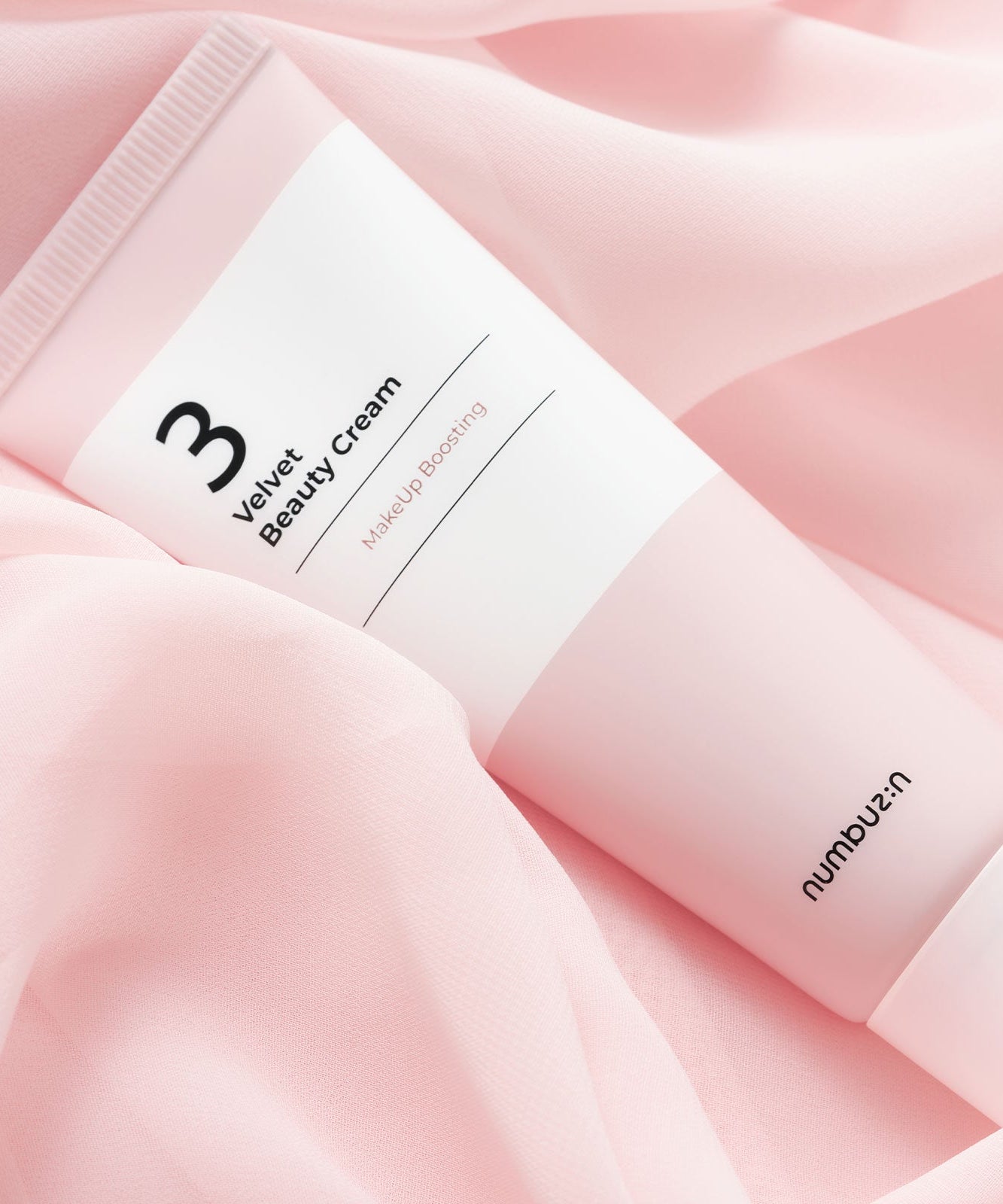 Tube de NUMBUZIN No.3 Velvet Beauty Cream sur tissu rose, soin de la peau luxueux