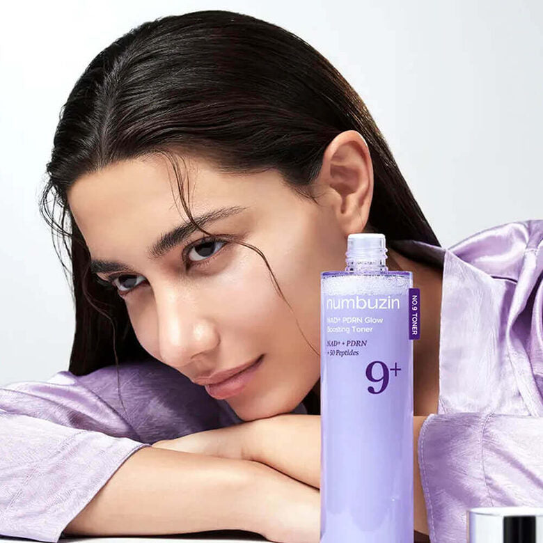 NUMBUZIN No.9 NMN PDRN Glow Boosting Toner 150ml, flacon au premier plan sur peau, modèle en fond clair.