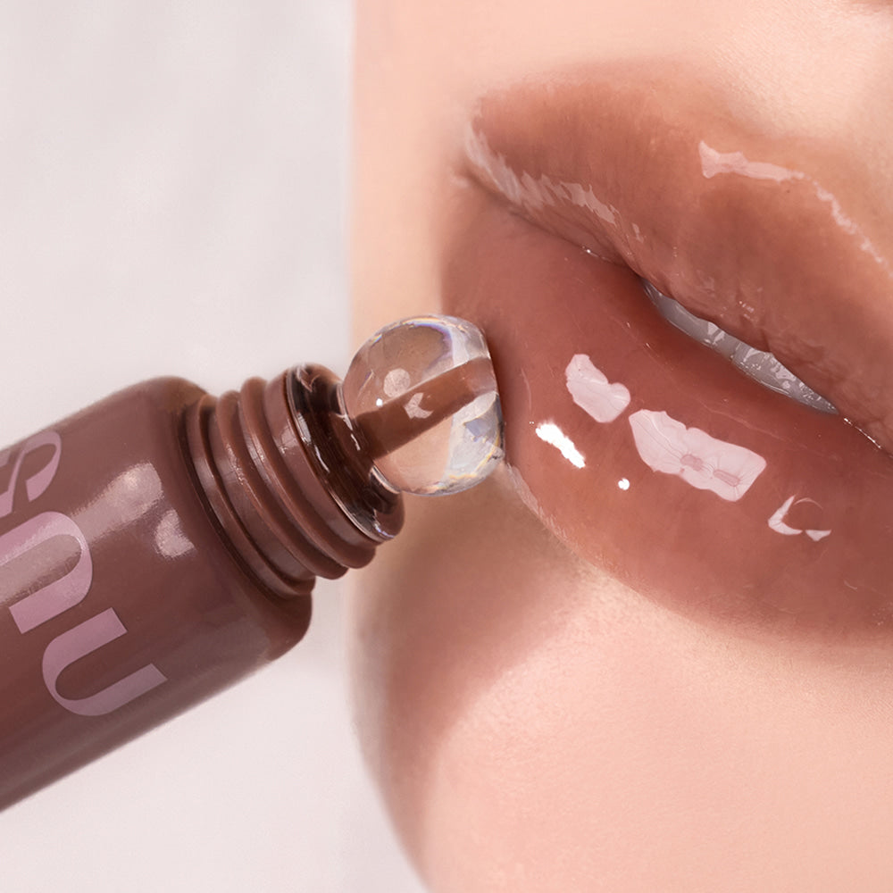 NUSE Nuzzle Reju Lip Gloss, gros plan sur l’embout appliquant un gloss brillant sur les lèvres, marque NUSE.