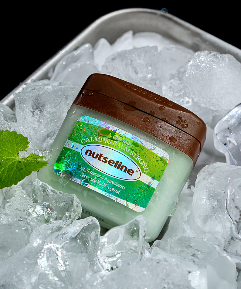 NUTSELINE Cica Nut Calming Balm Strong 50ml, baume apaisant NUTSELINE, sur glace avec menthe et contexte rafraîchissant.