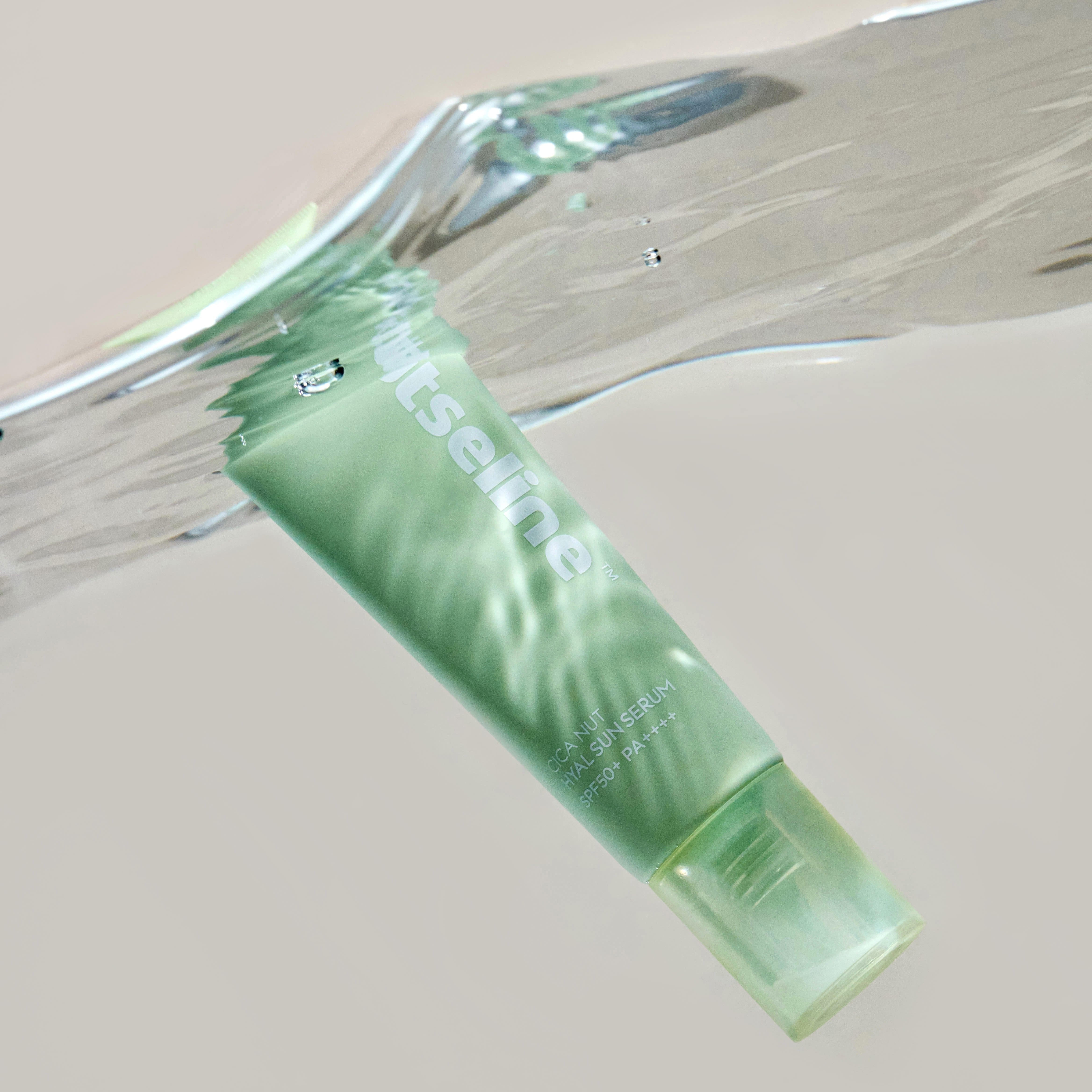 NUTSELINE Cica Nut Hyal Sun Serum 50ml, tube vert posé sur fond neutre, mise en scène cosmétique.