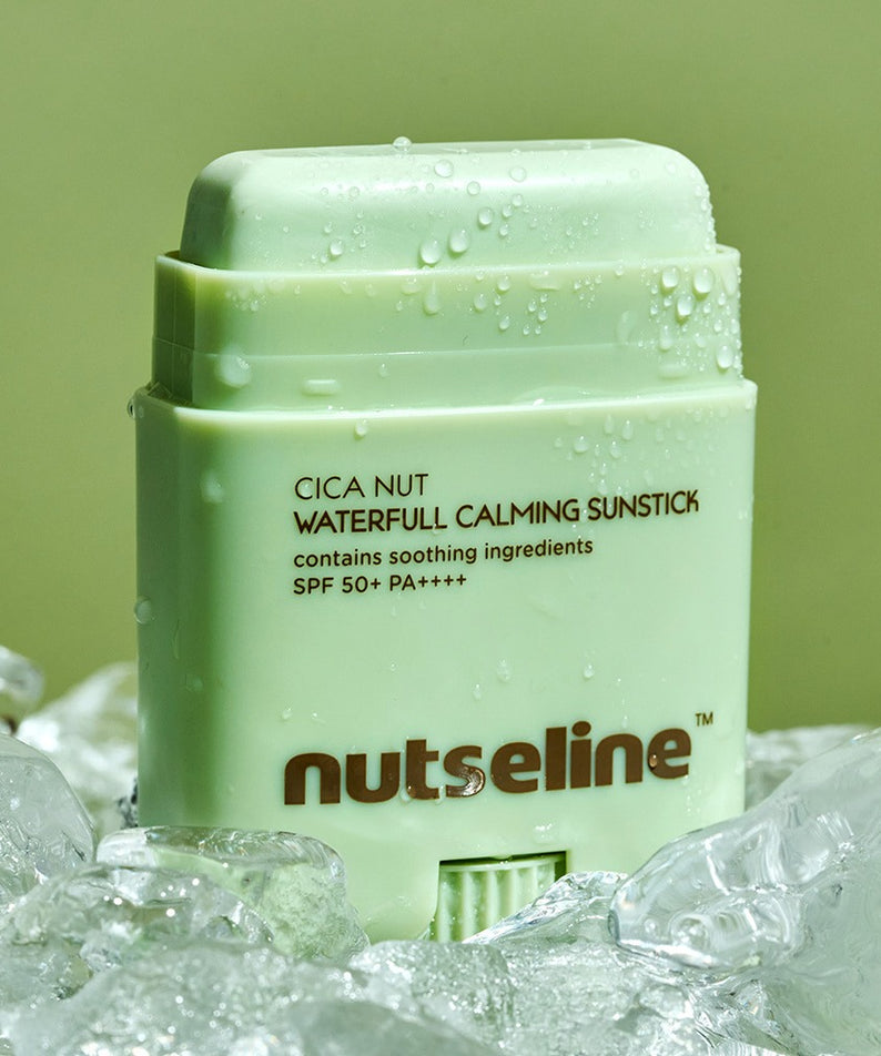 NUTSELINE Cica Nut Waterful Calming Sun Stick 20g, stick solaire apaisant de la marque NUTSELINE, sur fond vert avec gouttes d’eau.