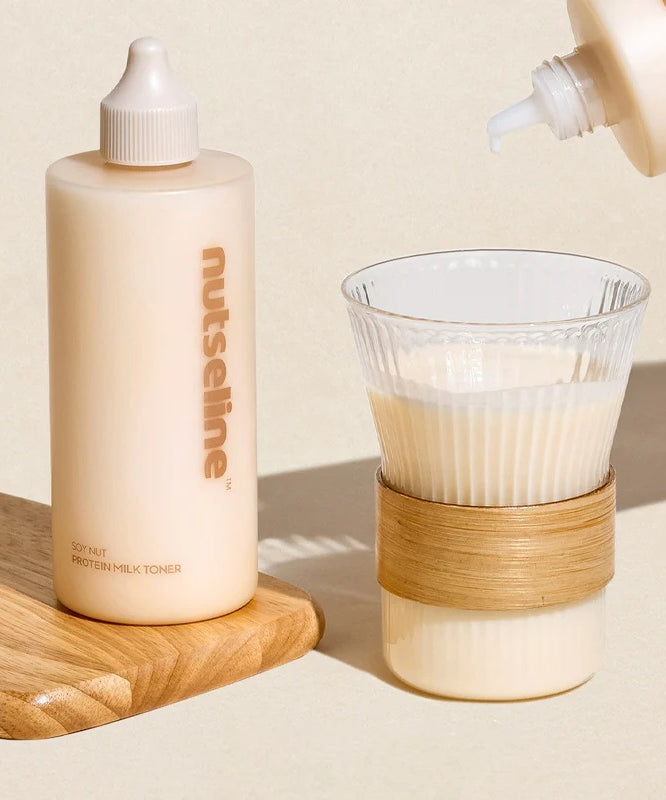 NUTSELINE Soy Nut Protein Milk Toner 300ml, flacon crème sur table bois, contexte beauté avec verseur et verre en arrière-plan.