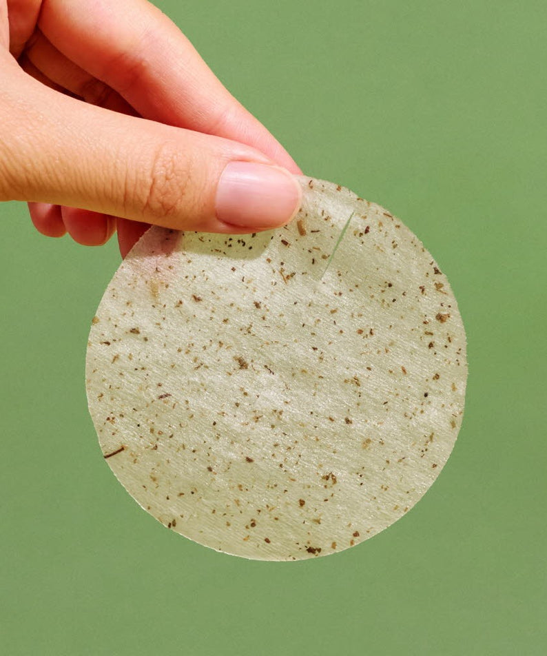 NUTSELINE Cica Calming Pad tenue par une main sur fond vert, montrant la texture naturelle du produit.