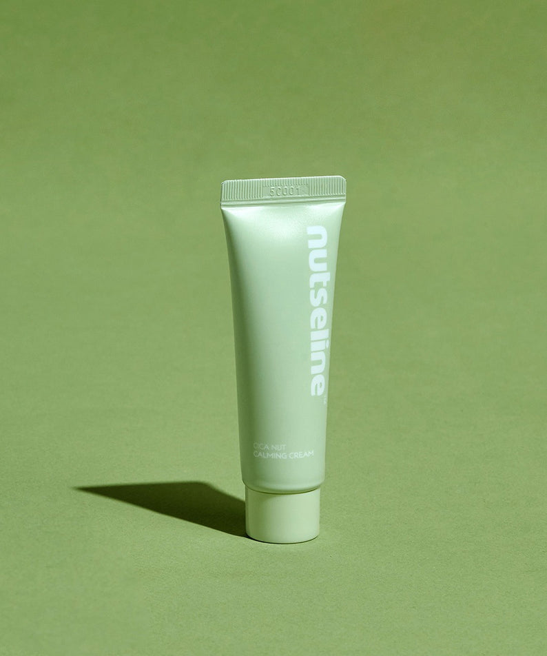 Crème apaisante NUTSELINE Cica Nut Calming Cream 25ml pour soin de la peau, tube vert posé sur un fond vert élégant.