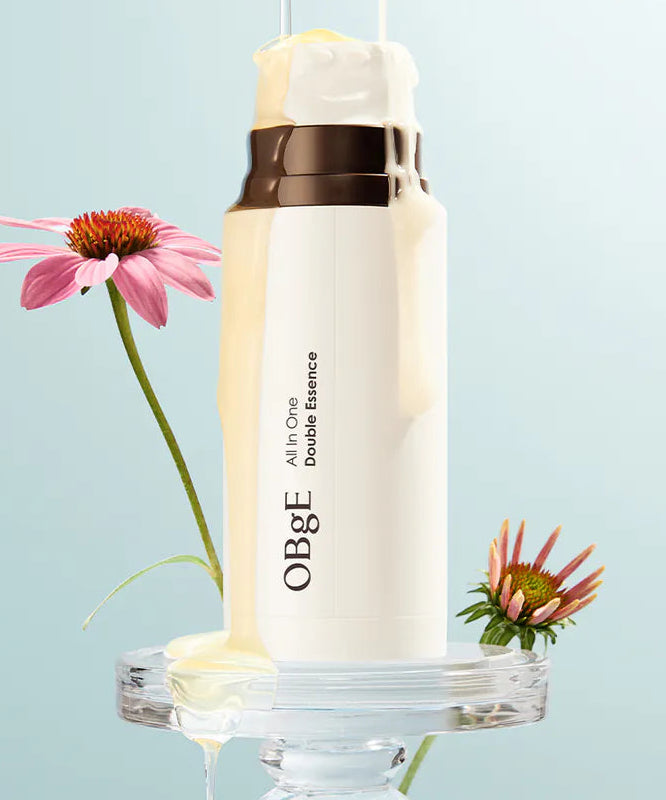 OBGE All-in-one double essence 100ml de la marque OBGE, flacon blanc sur décor bleu avec fleurs et gouttes d’essence.