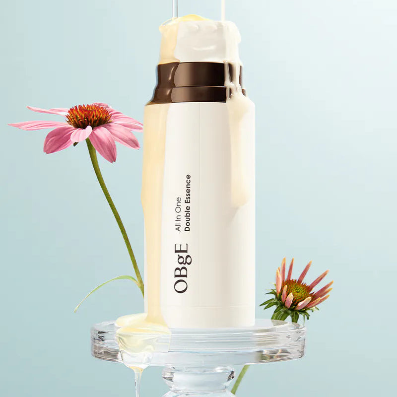 OBGE All-in-one double essence 100ml de la marque OBGE, flacon blanc sur décor bleu avec fleurs et gouttes d’essence.