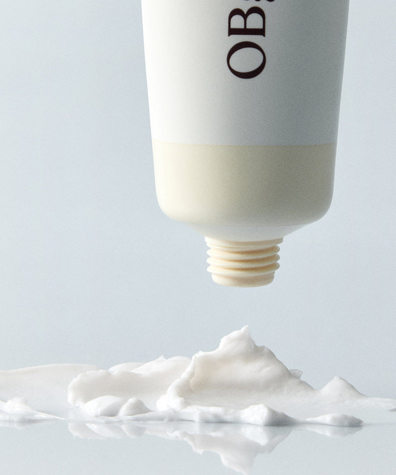 Décris l'image en français : OBGE Honey Butter Hand Cream 50ml d'OBGE, tube appliqué sur crème blanche sur fond clair.