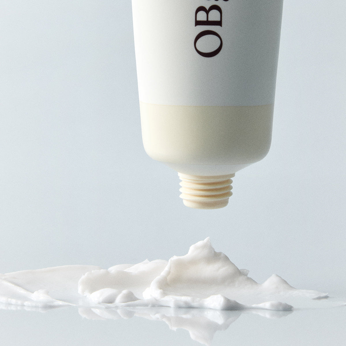 Décris l'image en français : OBGE Honey Butter Hand Cream 50ml d'OBGE, tube appliqué sur crème blanche sur fond clair.