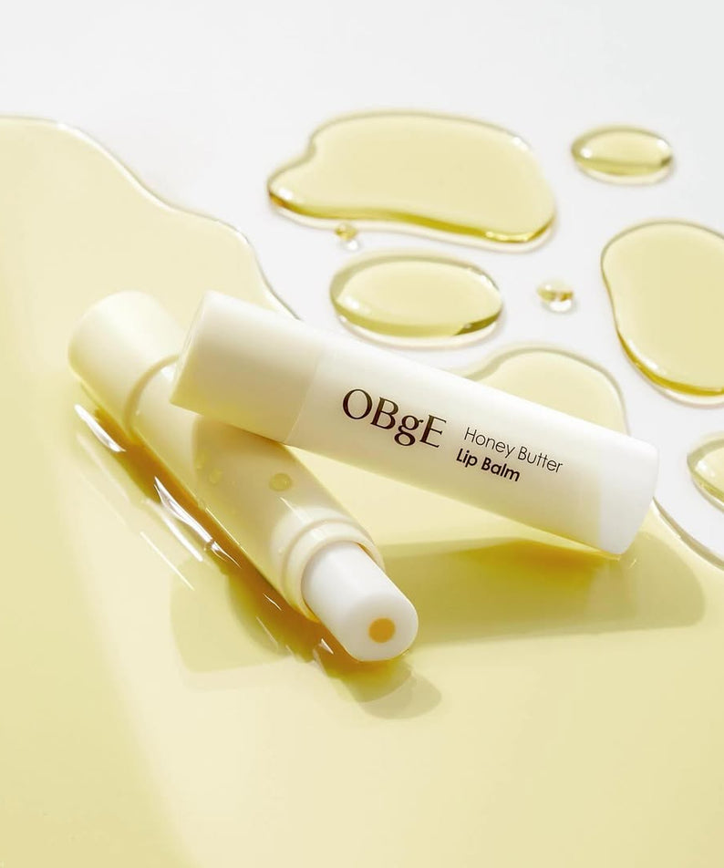 OBGE Honey Butter Lip Balm de la marque OBGE, tube blanc avec texture miel sur fond clair, gouttes et reflets dorés