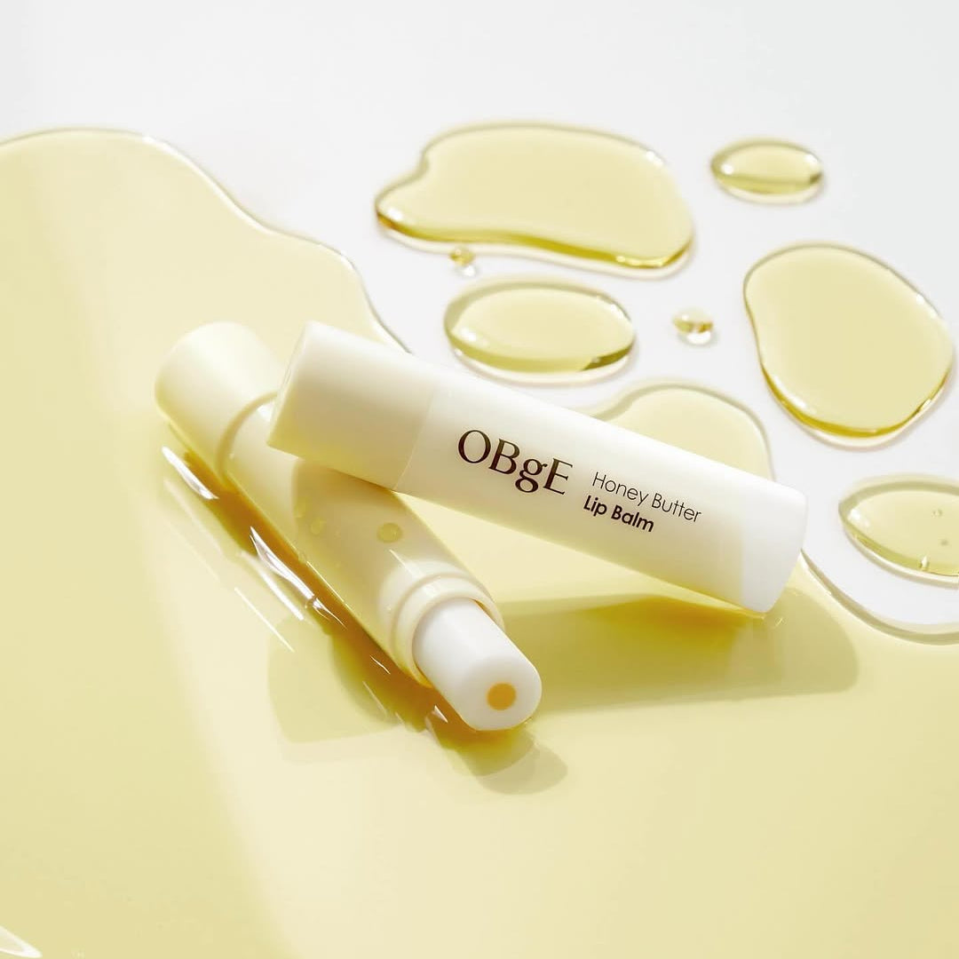 OBGE Honey Butter Lip Balm de la marque OBGE, tube blanc avec texture miel sur fond clair, gouttes et reflets dorés