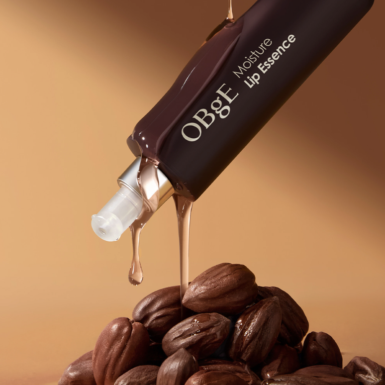 OBGE Moisture Lip Essence 10ml, tube brun sur grains de café, contexte visuel chaleureux et cosmétique