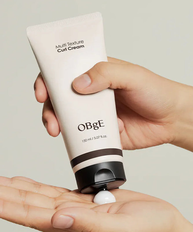 OBGE Multi-texture curl cream 150ml en main, tube beige crème coiffage boucles, fond clair, marque OBGE.
