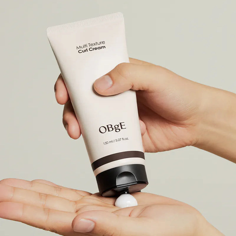 OBGE Multi-texture curl cream 150ml en main, tube beige crème coiffage boucles, fond clair, marque OBGE.