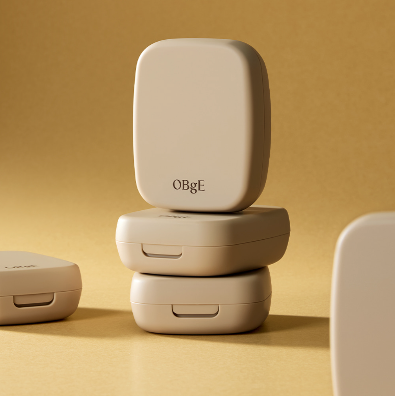 Décris l'image: OBGE Oil Control Finisher, pack crème beige OBGE sur fond sable, produit cosmétique en gros plan.