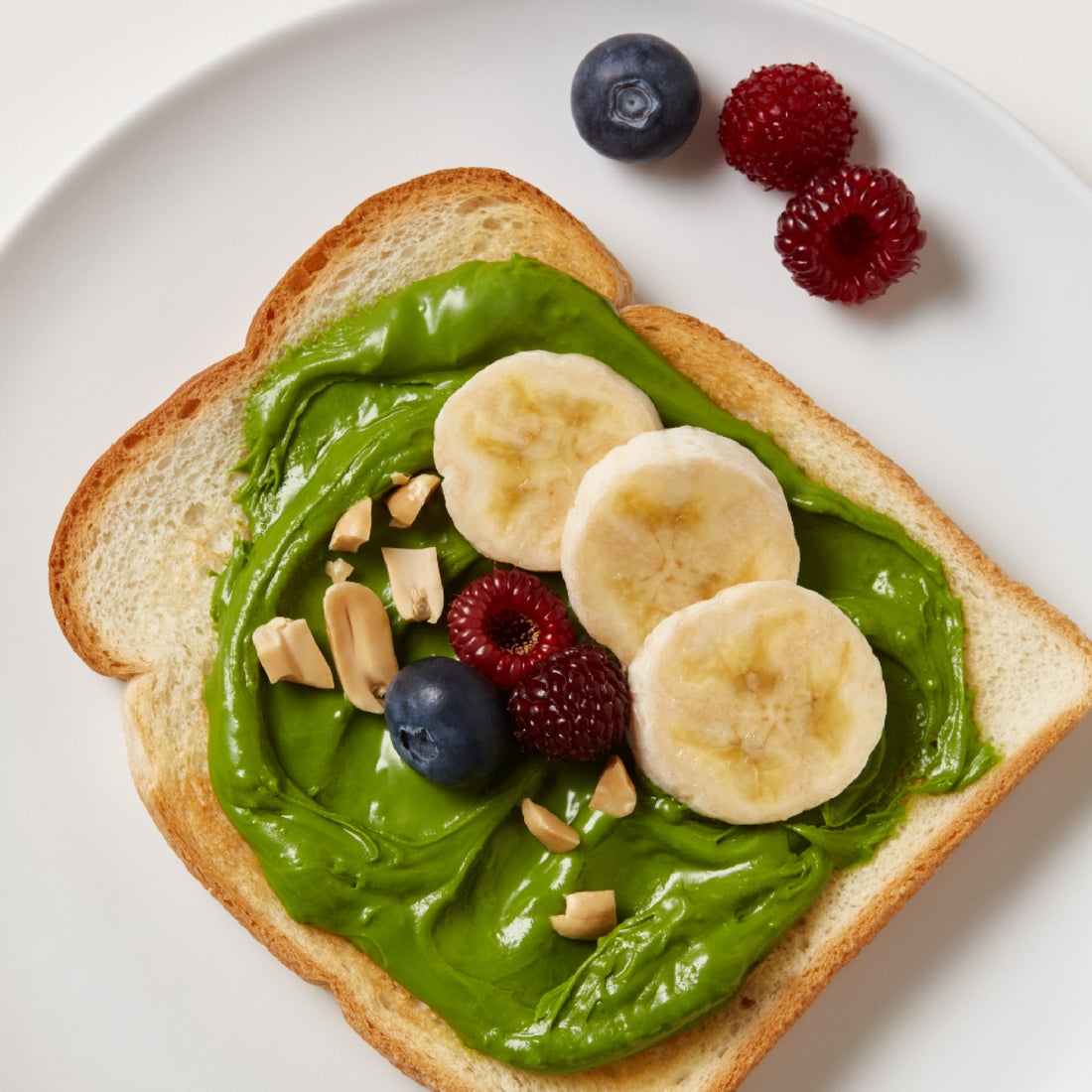 OSULLOC Green Tea Milk Spread 200g sur tartine verte, fruits frais (myrtilles, framboises), marque OSULLOC en contexte gourmand.
