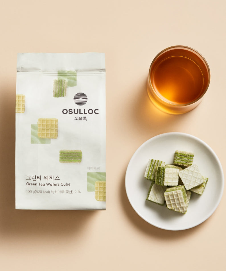 Sachet de OSULLOC Green Tea Wafers 100g avec thé vert servi en tasse et gaufrettes sur une assiette blanche.