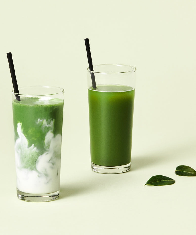 Deux verres de thé vert préparé, parfait pour OSULLOC Matcha Sticks 5 p, sur fond clair avec des feuilles décoratives.