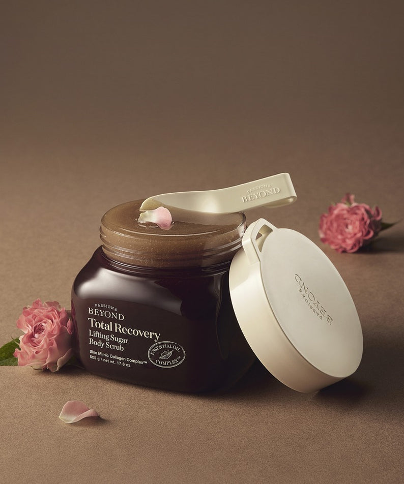 PASSION & BEYOND Total Recovery Lifting Body Scrub 500g, pot marron avec couvercle blanc, fleurs et pétales sur fond beige.