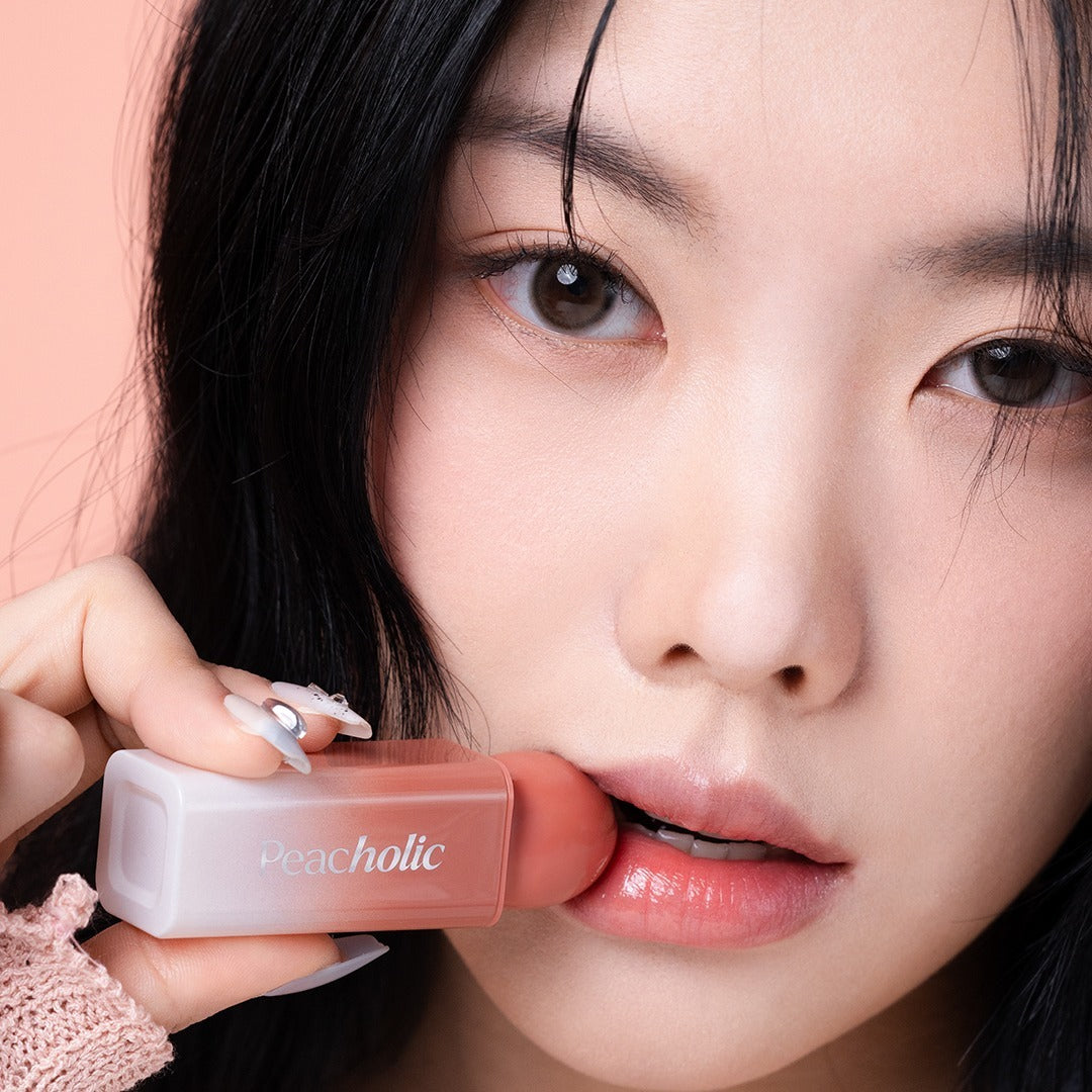 PEACHOLIC Water Glow Lip Tint par Peacheolic, gros plan lèvres hydratées tenant le tube, fond rose pastel