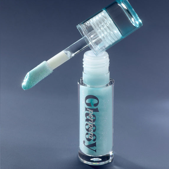 Décris l'image en français: PERIPERA Ink Glazing Lip Gloss Plumper, embout applicateur sur fond bleu, gloss brillant