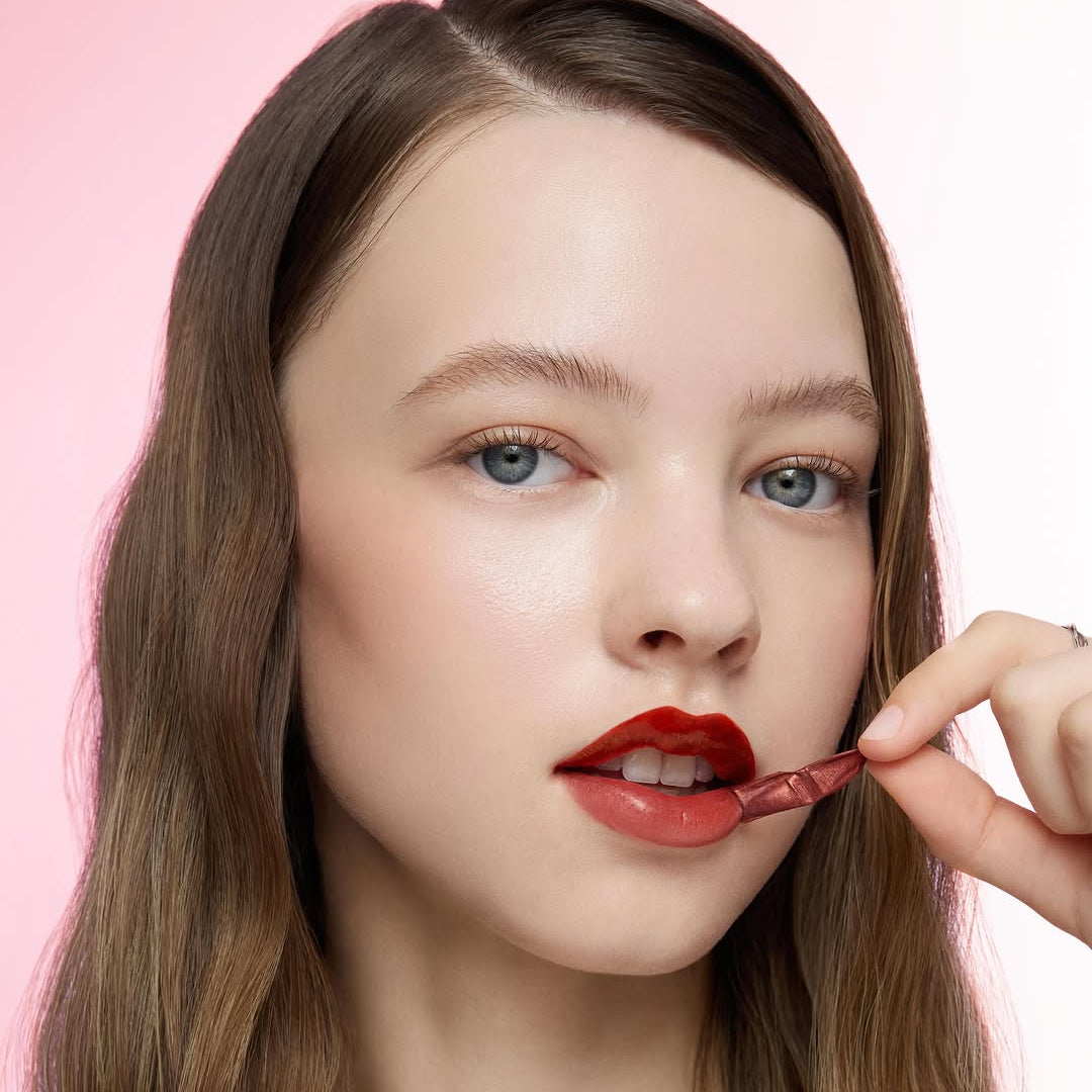 PERIPERA Ink Peel-Off Lip Stain, marque PERIPERA : pose maquillage lèvres rouges, main appliquant l’ink, fond rose
