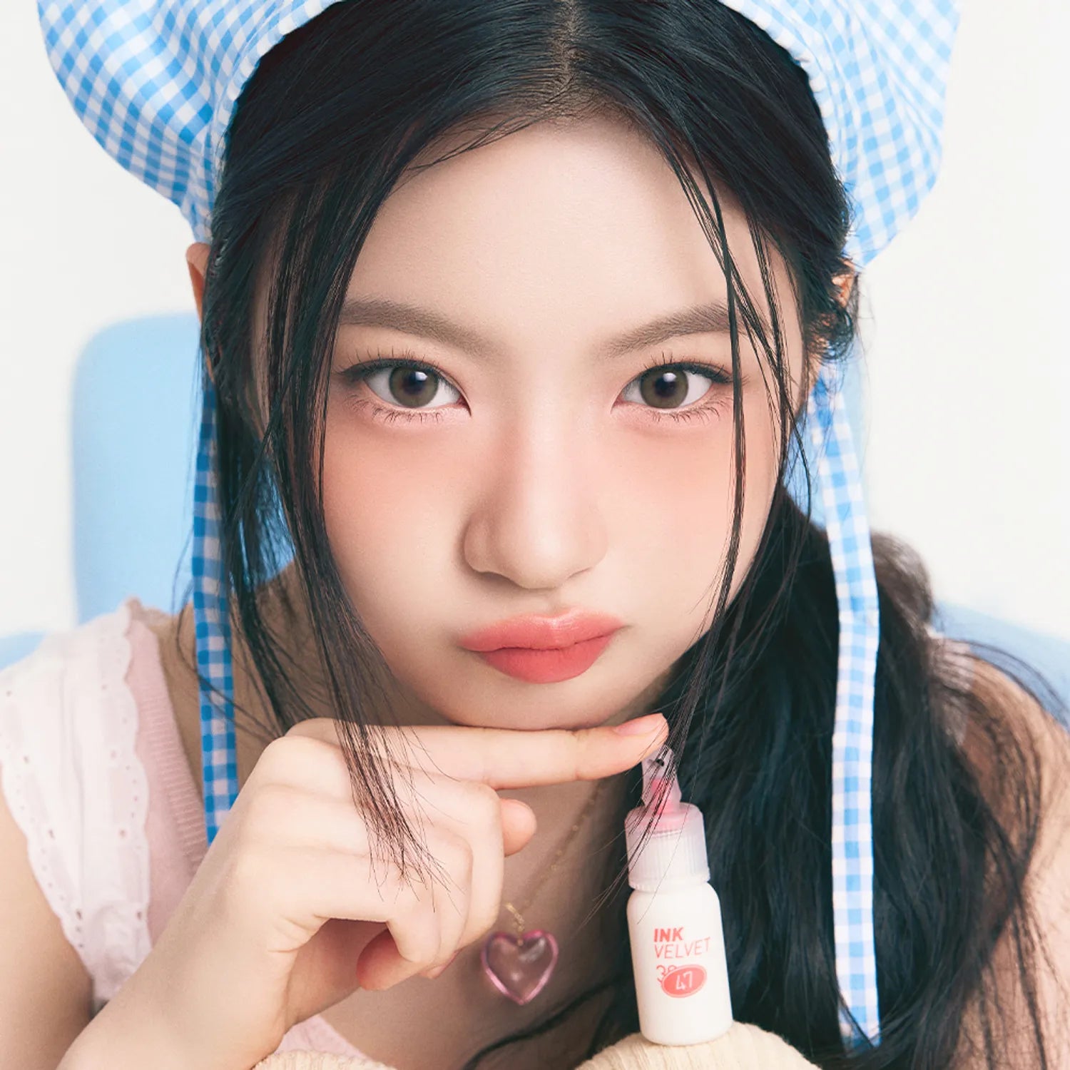 Portrait maquillage : PERIPERA Ink The Velvet de la marque PERIPERA, flacon rose sur fond bleu, style velours.