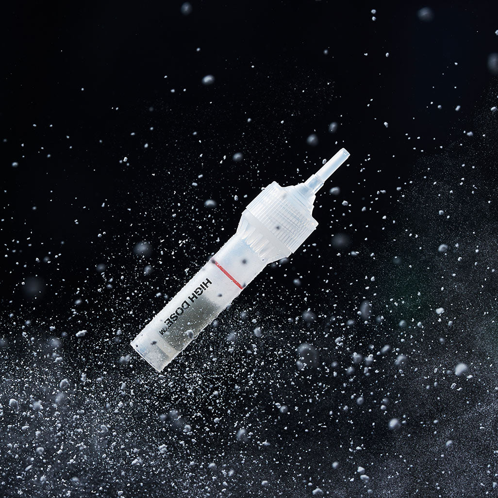 Décris l'image en français : PURCELL PixelBiome™ Booster Shot Powder 5ea de la marque PURCELL, poudre projetée sur fond noir.