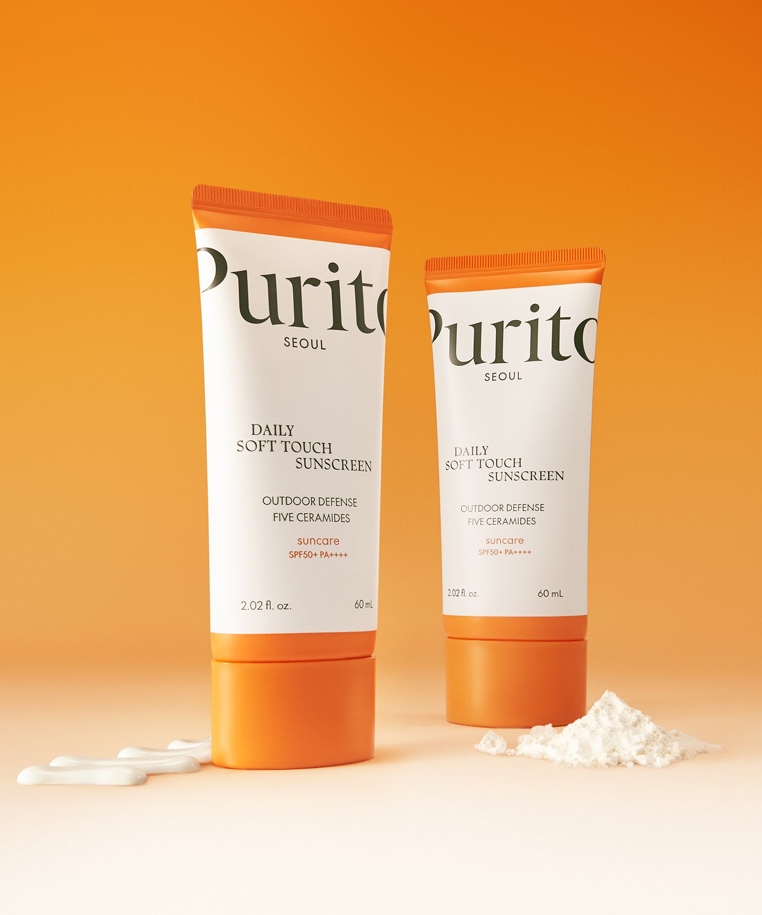 PURITO Daily Soft Touch Sun Cream SPF50+PA++++ de Purito, tubes crème solaire sur fond orange, texture crème.