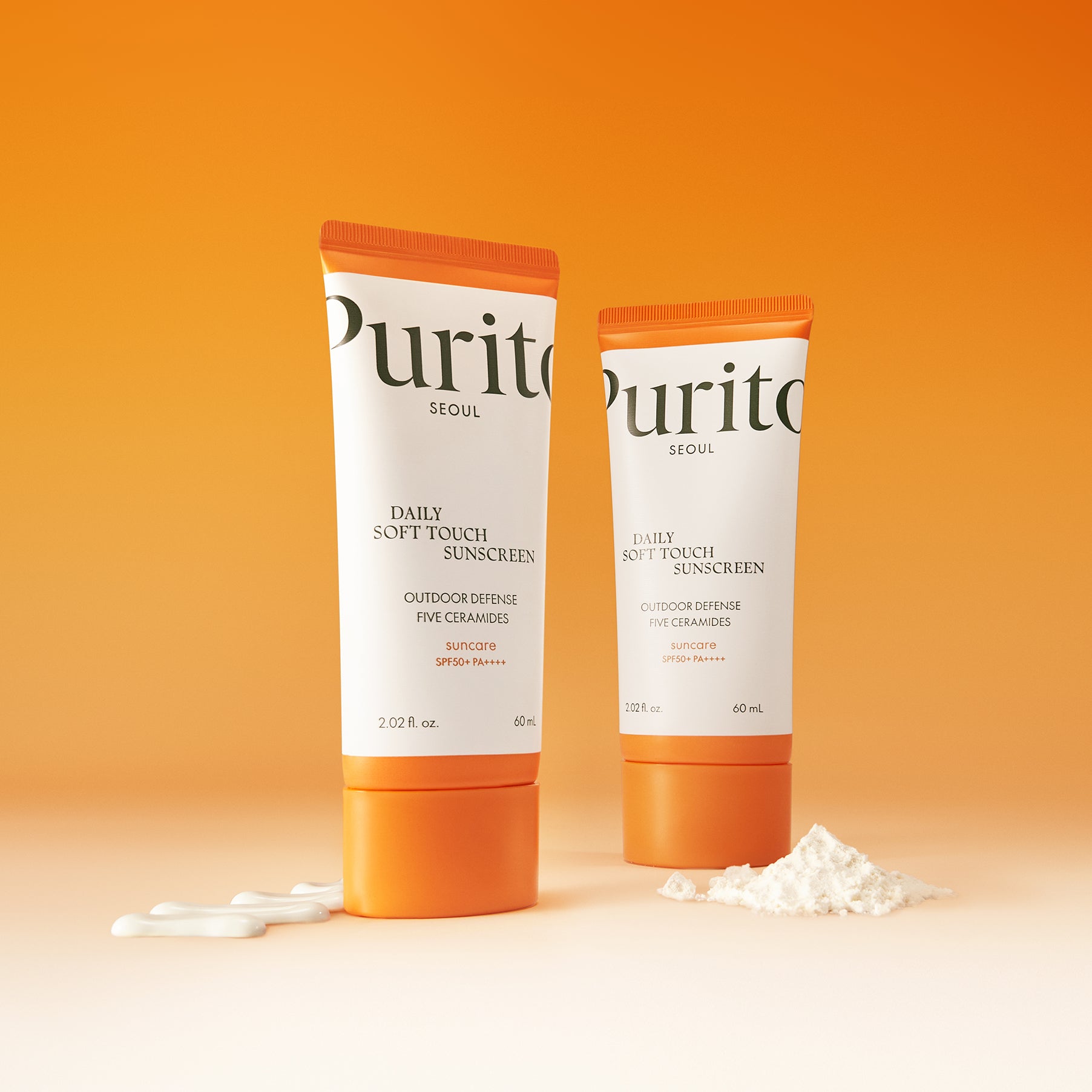 PURITO Daily Soft Touch Sun Cream SPF50+PA++++ de Purito, tubes crème solaire sur fond orange, texture crème.