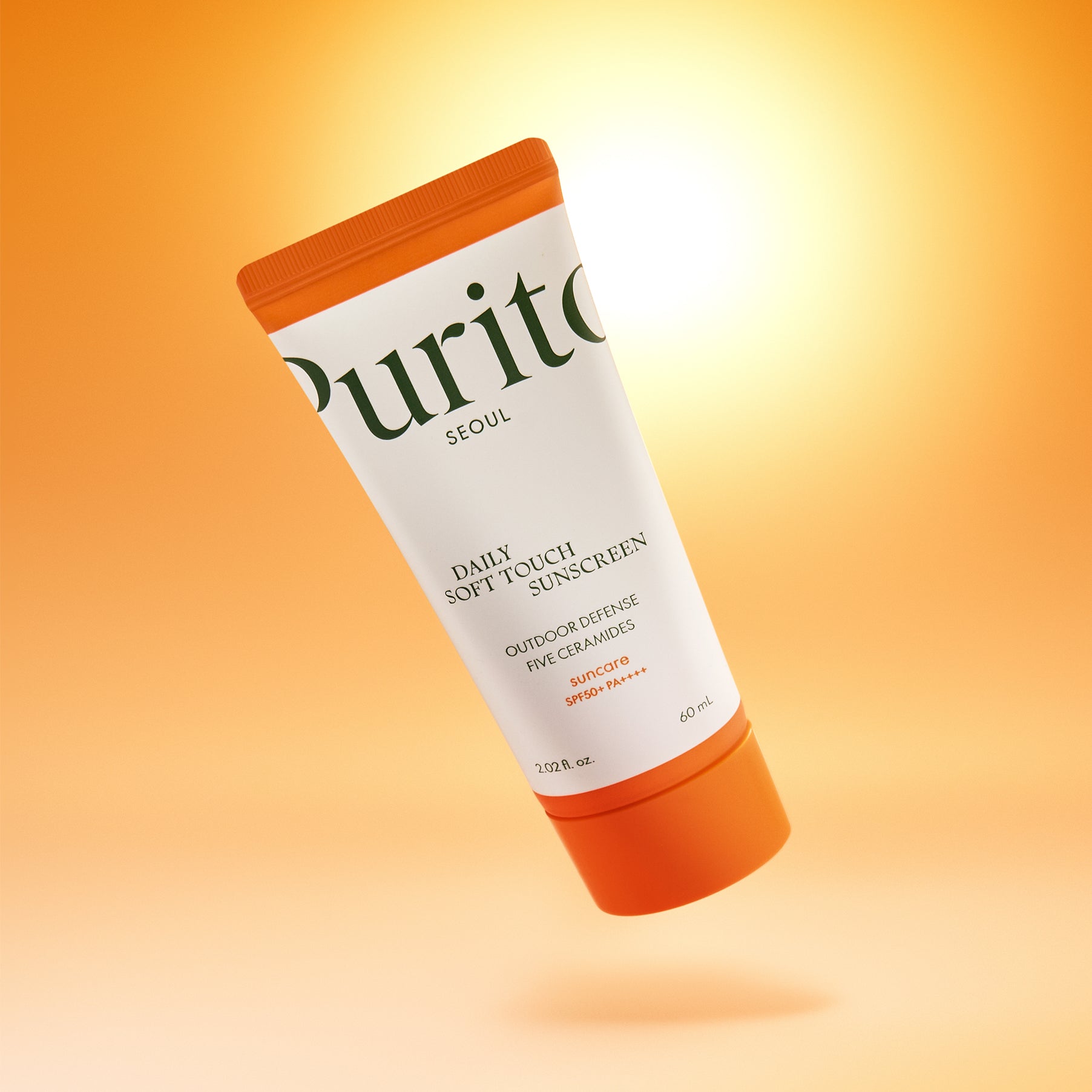 PURITO Daily Soft Touch Sun Cream SPF50+PA++++ de Purito, tube solaire orange sur fond jaune, éclairage doux, studio.