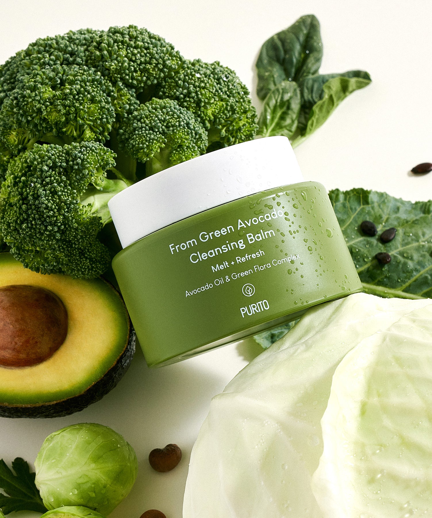 PURITO From Green Avocado Cleansing Balm 100ml : pot vert sur ingrédients verts (avocat, brocoli, feuilles), contexte spa naturel.